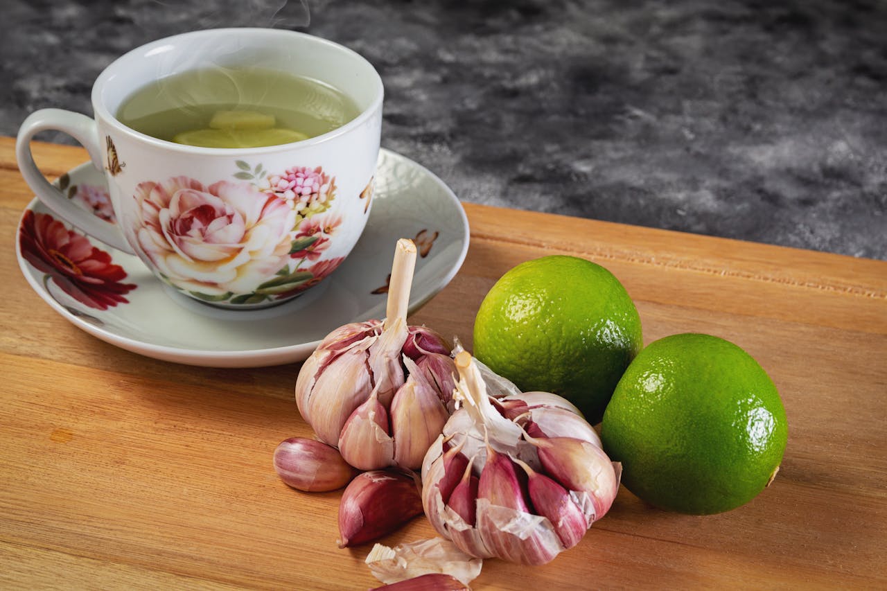 Close-up of herbal tea with garlic and limes on a wooden cutting board, perfect for food photography.