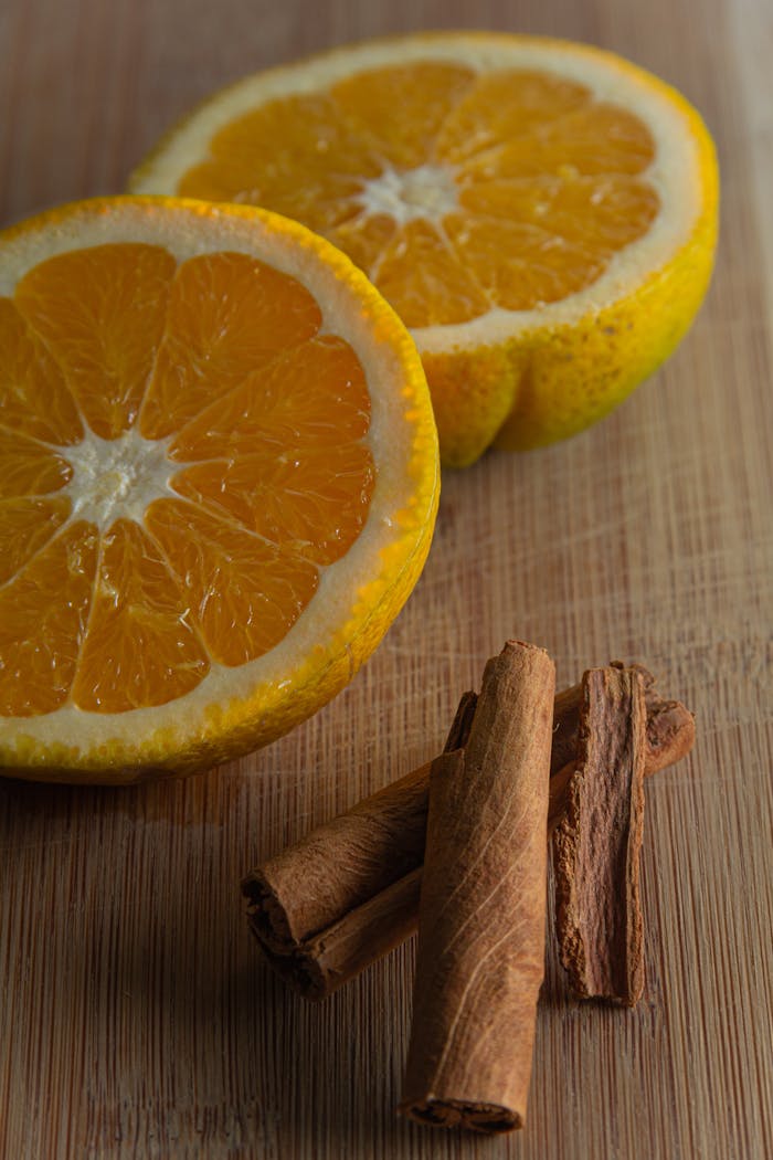 Close-up of sliced oranges and cinnamon sticks on a wooden board, showcasing vibrant colors and textures.